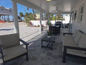 Eine überdachte Terrasse im Freien mit Esstisch, Stühlen und einer Couch.