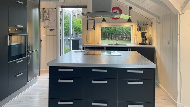 A modern kitchen with a large island, built-in appliances, and a view to the outdoors. - Amazing home in Rørvig with sauna (Rørvig)