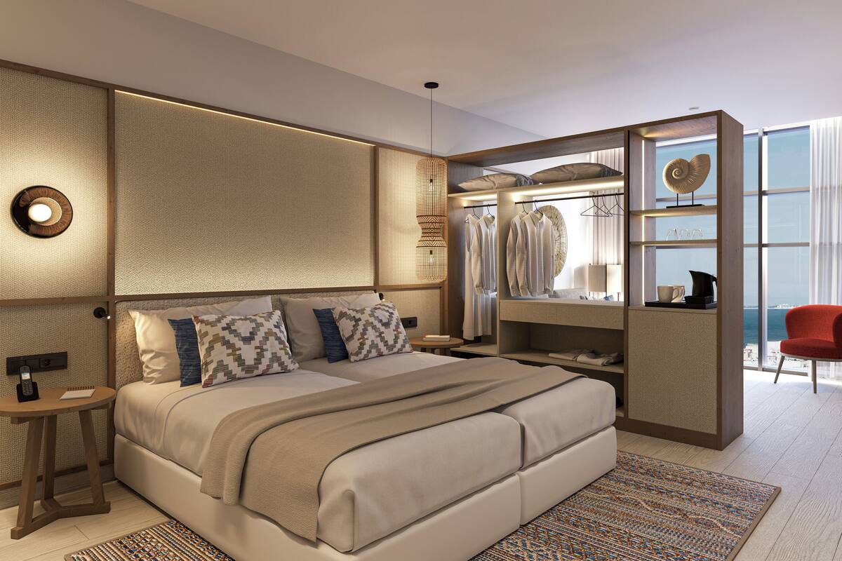 Une chambre d’hôtel moderne dotée d’un grand lit, d’un dressing et offrant une vue sur l’océan.