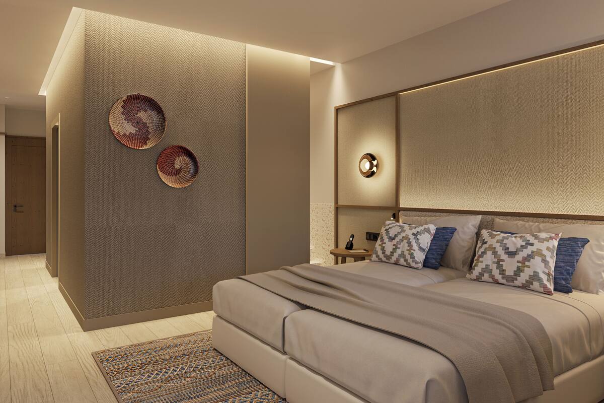 Une chambre d’hôtel moderne avec un grand lit, une table de chevet et un luminaire fixé au mur.