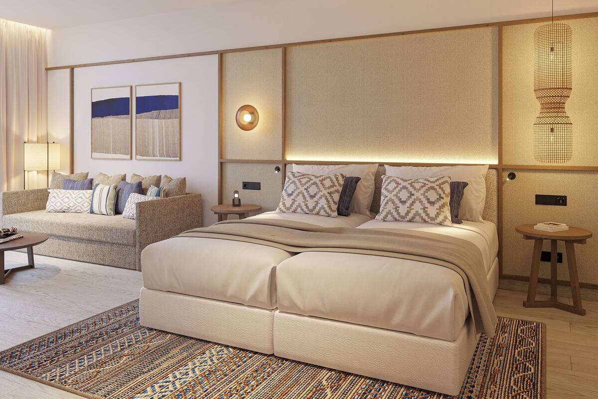 Une chambre d’hôtel moderne avec un grand lit, un canapé, une petite table et une lampe fixée au mur.