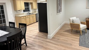 A modern kitchen with wooden cabinets, a black refrigerator, and a dining area with a black table and chairs. - Cozy 3/2 in downtown quaint Lake Mary, FL with AC and fenced in yard (Lake Mary)