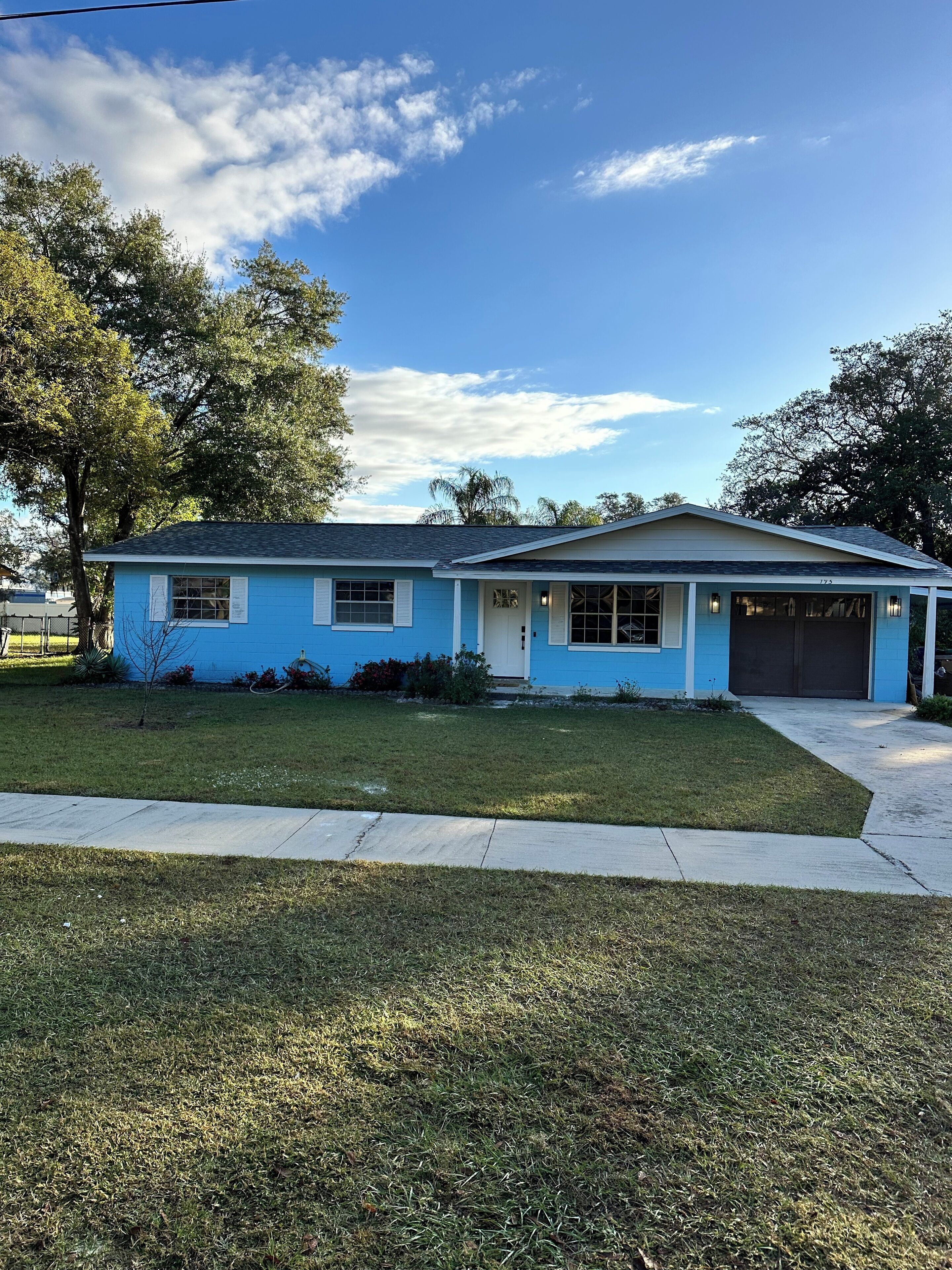 A single-story house with a garage, a front lawn, and a tree.
