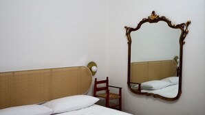 Une chambre à coucher avec un lit, une chaise et un miroir au mur.