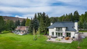 A two-story house with a stone exterior, a large deck, and a well-maintained lawn. - Fairway Twelve Retreat (Sun Valley)