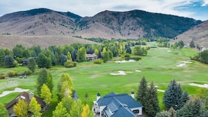 A golf course with a clubhouse, surrounded by mountains and trees. - Fairway Twelve Retreat (Sun Valley)