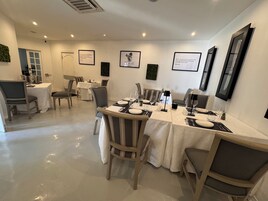 Un comedor con mesas dispuestas para cuatro, sillas y citas enmarcadas en las paredes.
