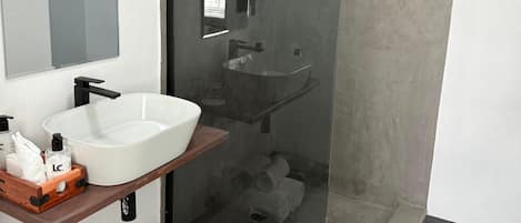 A modern bathroom with a glass-enclosed shower, a white sink, and a mirror.