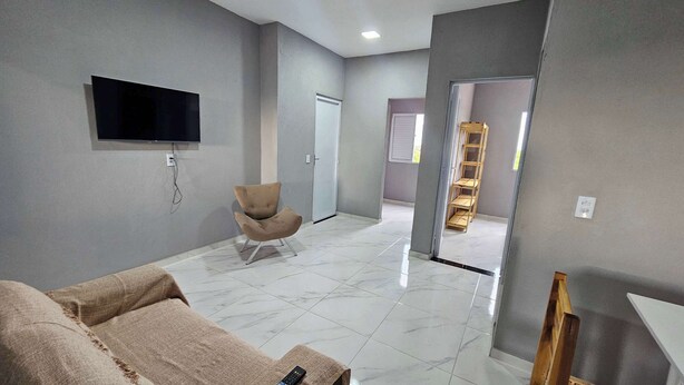 A modern living room with a flat-screen TV mounted on the wall, a comfortable armchair, and a sofa with a blanket. - Waterview Apartment w/Ocean Breezes Near Jeri (Preá - CE)