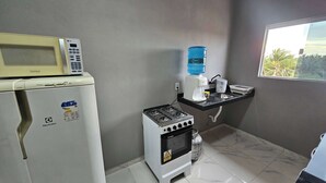 A compact kitchen with a refrigerator, a water dispenser, a stove, and a microwave. - Waterview Apartment w/Ocean Breezes Near Jeri (Preá - CE)