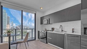 A modern kitchen with a large window, stainless steel appliances, and a city view. - Luxury Miami Studio with Rooftop Pool (Miami)