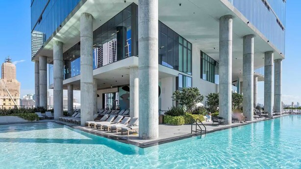 A modern hotel with a rooftop infinity pool, large windows, and a view of the city skyline. - Luxury Miami Studio with Rooftop Pool (Miami)