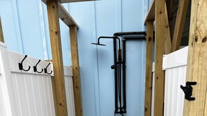 Eine Holzterrasse mit einer Bank und einer Duschkabine aus Metall.