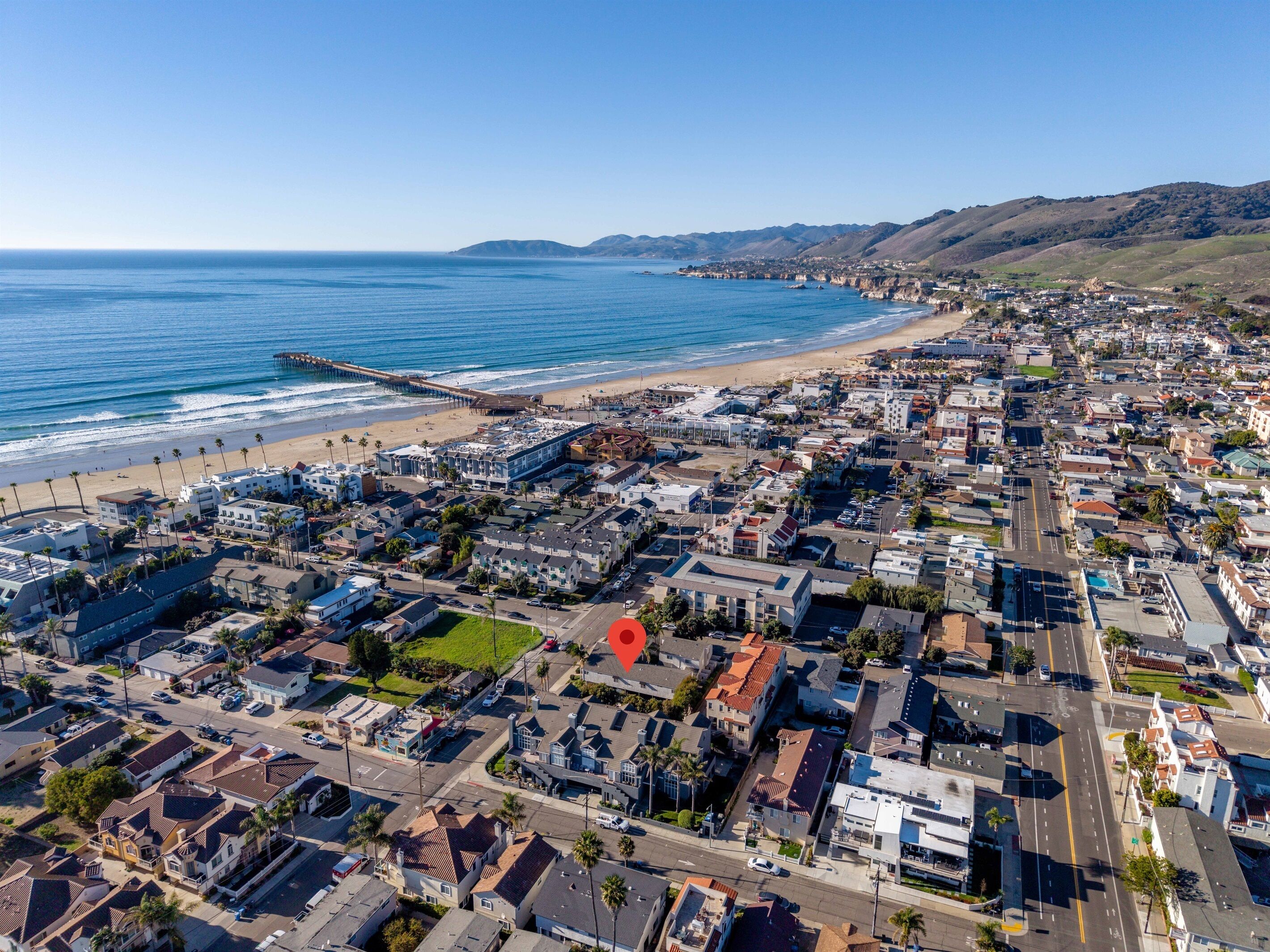 Vue aérienne d’une ville côtière avec une plage, des immeubles résidentiels et une jetée.