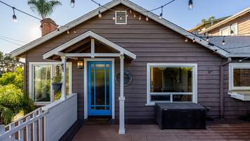 A house with a blue door, a porch with a bench, and string lights.