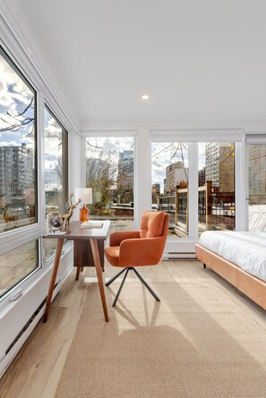 A modern bedroom with a large window, a bed, a chair, and a small table. - Montréal Downtown Haven | Walk to All Attractions (Montréal)