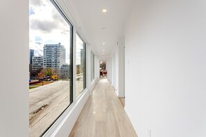 A corridor with large windows, a wooden floor, and a view of a cityscape. - Montréal Downtown Haven | Walk to All Attractions (Montréal)