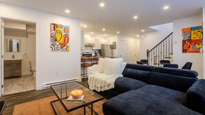 A modern living room with a sofa, a glass coffee table, and abstract art on the walls. - Chic City Hideaway | Vibrant Heart of Montréal (Montreal)