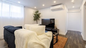 A modern bedroom with a bed, a TV, and an air conditioning unit. - Chic City Hideaway | Vibrant Heart of Montréal (Montreal)