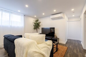 A modern bedroom with a bed, a TV, and an air conditioning unit. - Chic City Hideaway | Vibrant Heart of Montréal (Montreal)
