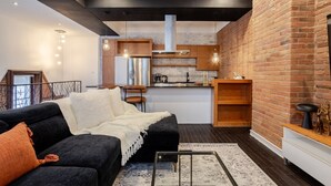 A modern living room with a black sofa, a white throw blanket, and a coffee table. - Elegant Downtown Stay | Near Bell Centre MTL (Montreal)