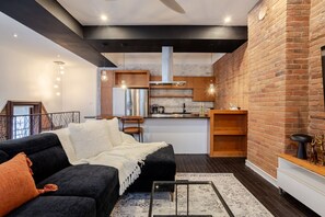 A modern living room with a black sofa, a white throw blanket, and a coffee table. - Elegant Downtown Stay | Near Bell Centre MTL (Montreal)