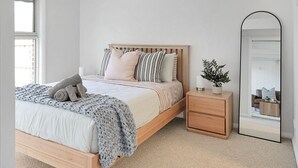 A bedroom with a bed, bedside table, and a large mirror. - Retreat on Hitchcock; 3 bedroom, 2 bathroom, pet friendly, central Barwon Heads w Parking (Barwon Heads)