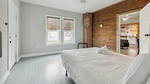 Un dormitorio con una cama, un ventilador de techo y vistas a la cocina.