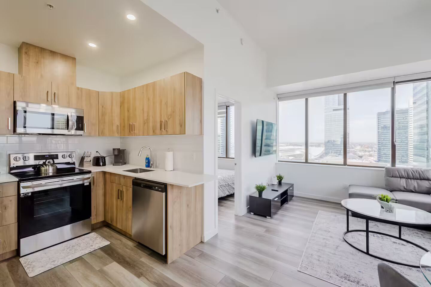 Une cuisine moderne avec des meubles en bois, des appareils en acier inoxydable et une grande fenêtre donnant sur la ville.
