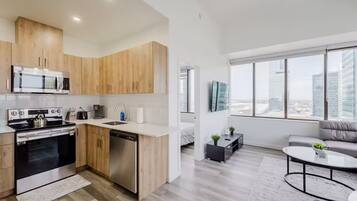 Une cuisine moderne avec des meubles en bois, des appareils en acier inoxydable et une grande fenêtre donnant sur la ville.
