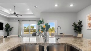 Eine moderne Küche mit Granit Arbeitsplatten, Edelstahlspülen und einem Deckenventilator.