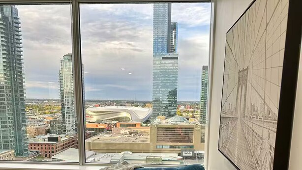 Un saló modern amb un finestra gran que ofereix una vista de la ciutat, un sofà seccional blau i un mapa emmarcat a la paret.