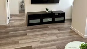 Un saló modern amb televisió de pantalla plana penjada a la paret, un moble de televisió negre i una taula de cafè de marbre.