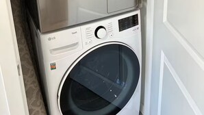 Een gestapelde wasmachine en droger met bedieningspaneel en een keuringssticker.