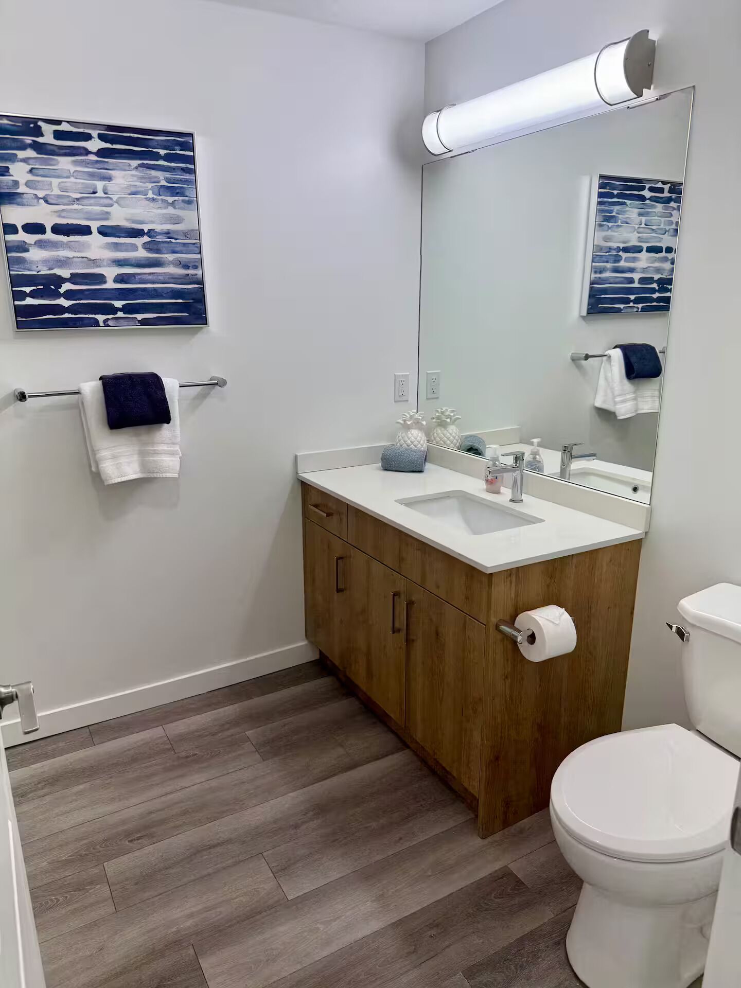 A modern bathroom with a wooden vanity, white sink, and a toilet.