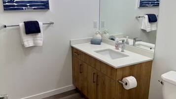 A modern bathroom with a wooden vanity, white sink, and a toilet.
