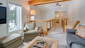 Un salon spacieux avec un plafond haut, une cheminée, un téléviseur et un coin salon confortable avec un canapé et des fauteuils.