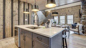 A modern kitchen with a central island, stainless steel appliances, and pendant lighting. - Indoor Pool, Hot Tub! 'The Smoky Luxe Retreat' (Pigeon Forge)