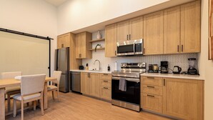 A modern kitchen with wooden cabinets, stainless steel appliances, and a dining area with a table and chairs. - 2-bedroom apartment in terrific Montclair with AC and fitness room (Montclair)