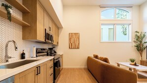 A modern kitchen with wooden cabinets, a stainless steel sink, and a herringbone-patterned backsplash. - 2-bedroom apartment in terrific Montclair with AC and fitness room (Montclair)