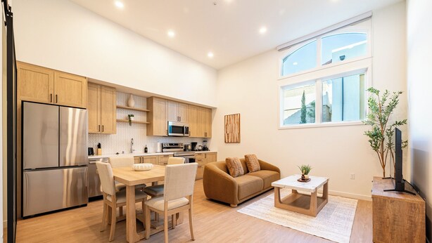 A modern kitchen with wooden cabinets, stainless steel appliances, and a dining area with a table and chairs. - 2-bedroom apartment in terrific Montclair with AC and fitness room (Montclair)