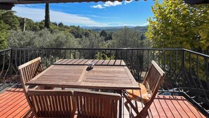 Une terrasse en bois avec une table et des chaises, offrant une vue sur un paysage boisé.