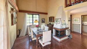 Un coin repas avec une cheminée, une table à manger avec des chaises et une fenêtre avec des rideaux.