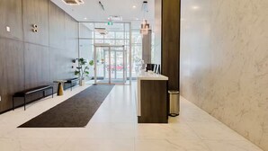 Eine moderne Lobby mit Empfangstresen, einer Sitzecke und Glastüren zum Außenbereich.