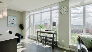 Ein modernes Wohnzimmer mit großem Fenster, Essbereich und Blick auf die Stadt.