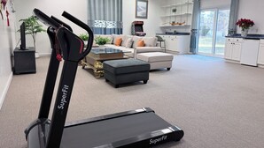 Ein modernes Wohnzimmer mit Laufband, Sofa, Couchtisch und Küchenbereich.