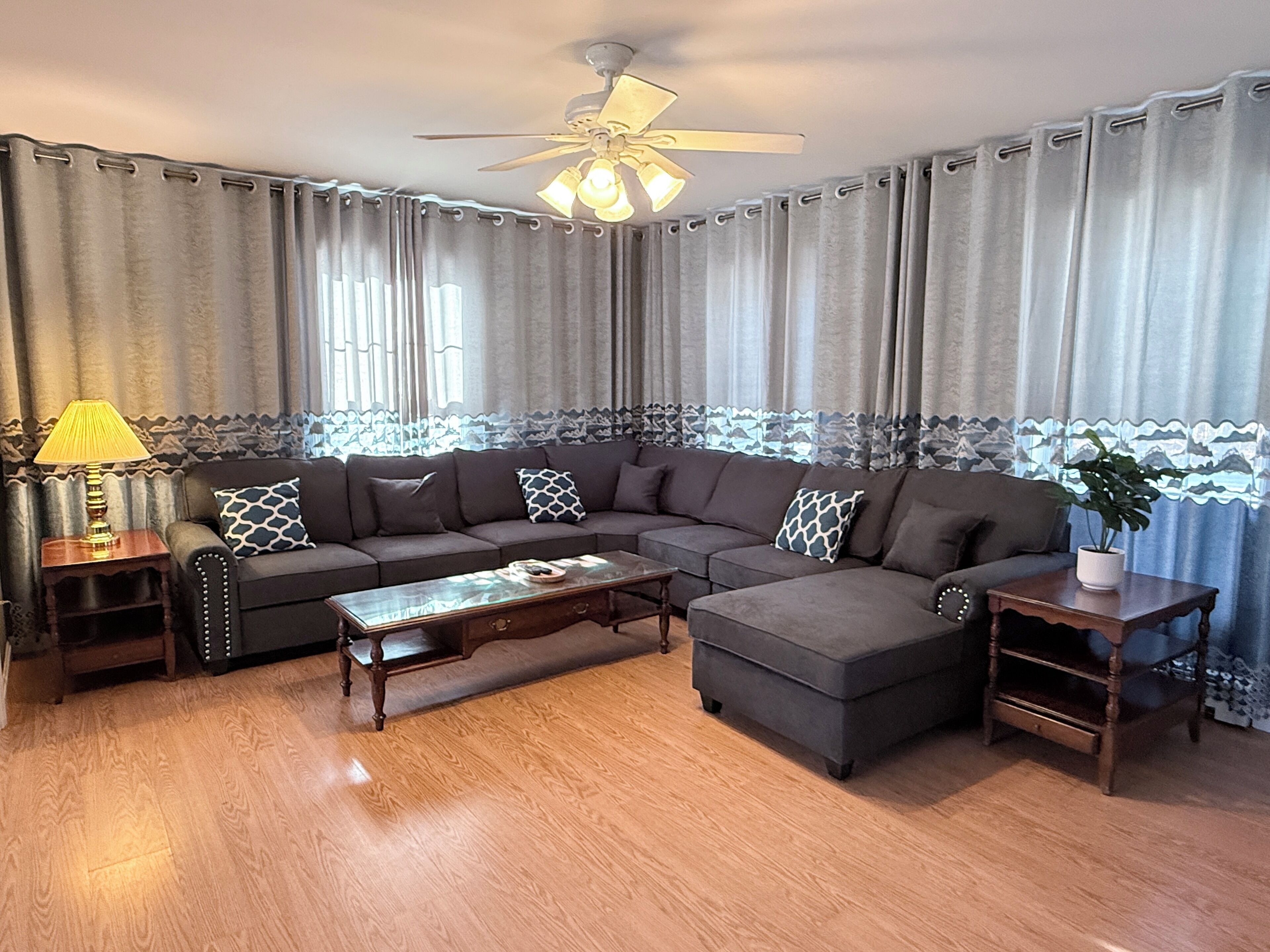 A living room with a sectional sofa, a coffee table, a side table, and a ceiling fan.