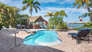 Una piscina con lettini, un'area barbecue e vista sull'acqua.