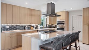 Una cucina moderna con mobili in legno, un'isola centrale ed elettrodomestici integrati.