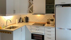 Una cocina moderna con gabinetes blancos, un lavamanos de acero inoxidable, un horno empotrado y un refrigerador.